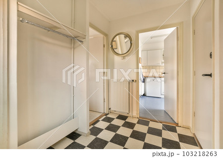 an empty room with a black and white checkered floor, mirror on the wall and door to the left an empty room with a black and white checkered floor, mirror on the wall and door to the left 103218263