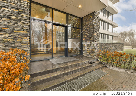 the outside of a modern house with stone walls and glass doors that look like it's going to fall 103218455