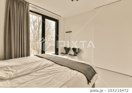a bedroom with a bed, chair and large window looking out to the trees in the room is very clean 103218472