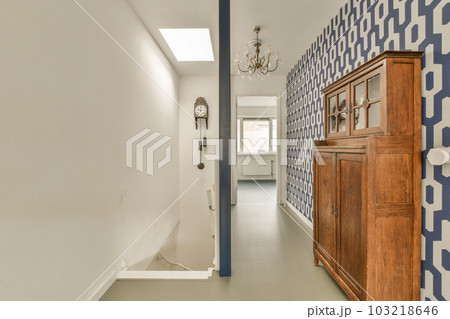 a long hallway with blue and white wallpapers on the walls, along an open door leading to another room 103218646