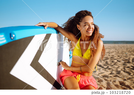 Woman surfer walks with a board on the sandy beach. Extreme sport. Travel, weekend, lifestyle. Woman surfer walks with a board on the sandy beach. Extreme sport. Travel, weekend, lifestyle. 103218720