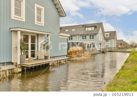 some houses on the side of a body of water in front of a house with two boats parked along it some houses on the side of a body of water in front of a house with two boats parked along it 103219013