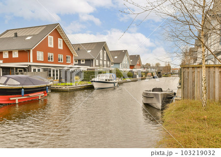 some boats in the water and houses on the other side of the river, with one boat docked at the end some boats in the water and houses on the other side of the river, with one boat docked at the end 103219032