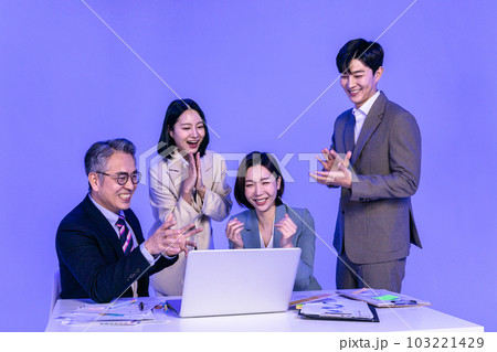 Asian Korean senior, middle aged and young male and female colleagues models in business attire, neon purple studio background, happy looking at the laptop 103221429