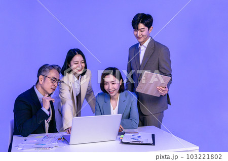 Asian Korean senior, middle aged and young male and female colleagues models in business attire, neon purple studio background, meeting while looking at a laptop 103221802