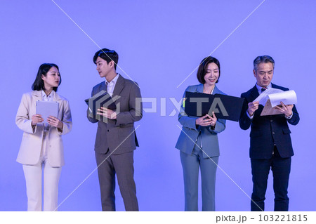 Asian Korean senior, middle aged and young male and female colleagues models in business attire, neon purple studio background, looking at the tablet and the documents 103221815