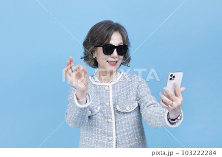 active young senior Korean Asian woman with sunglasses using smartphone active young senior Korean Asian woman with sunglasses using smartphone 103222284