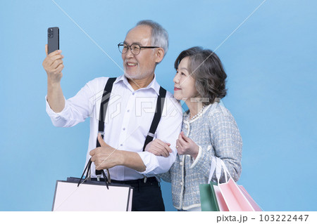 active young senior Korean Asian couple holding shopping bags and smartphone active young senior Korean Asian couple holding shopping bags and smartphone 103222447