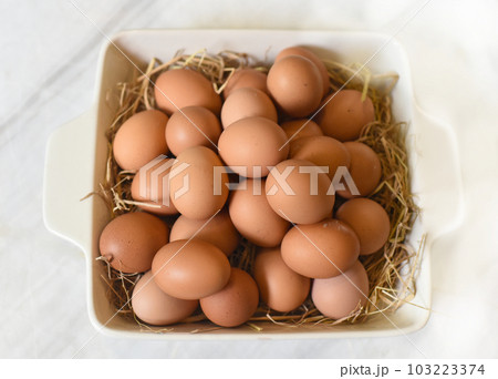 Pile of eggs on straw in a pan closeup Pile of eggs on straw in a pan closeup 103223374
