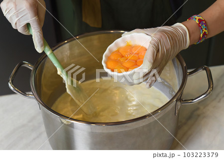 A hands in rubber gloves stirring dough for a cake in a saucepan 103223379