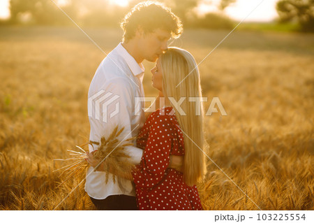 Young happy couple hugging on a wheat field, on the sunset. Enjoying time together. 103225554