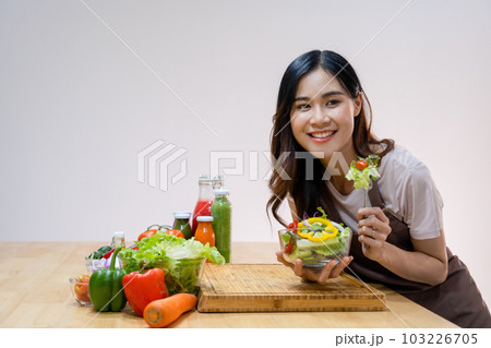 Woman eating homemade salad in kitchen. Woman eating homemade salad in kitchen. 103226705