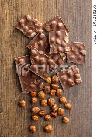 Broken chocolate bars with  nuts on wooden table.. Top view. 103228205