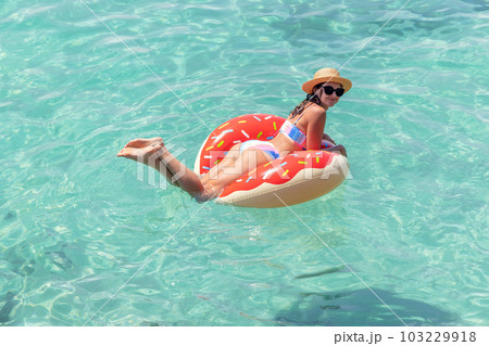 Beautiful woman with inflatable donut in sea Beautiful woman with inflatable donut in sea 103229918