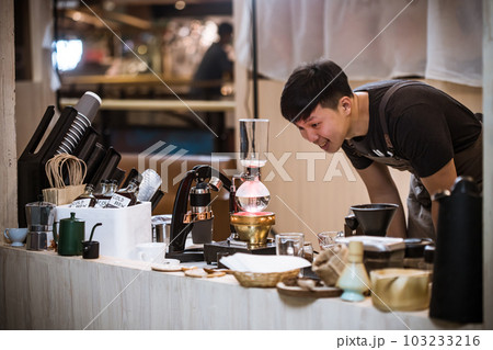 Professional coffee maker - Barista using coffee siphon brewing hot espresso at coffee shop coffee brewing syphon alternative method. Startup Business Concept. Professional coffee maker - Barista using coffee siphon brewing hot espresso at coffee shop coffee brewing syphon alternative method. Startup Business Concept. 103233216