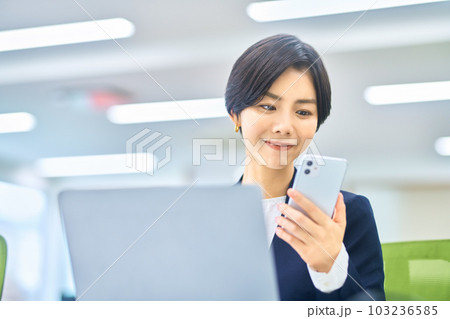 オフィスでスマホを操作するスーツ姿のミドルビジネスウーマン 103236585