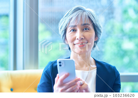 オフィスのソファーでスマホを操作するミドルビジネスウーマン オフィスのソファーでスマホを操作するミドルビジネスウーマン 103236620