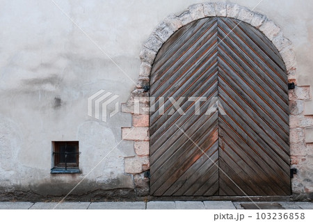 vintage wooden door on the gray wall. a large wooden door on the side of a building 103236858