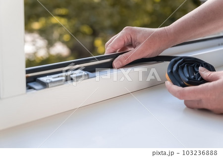 a person installing a window seal on a window. Heat saving concept. 103236888
