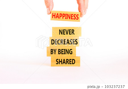 Happiness symbol. Concept words Happiness never decreases by being shared on wooden block. Businessman hand. Beautiful white table white background. Motivational Happiness concept. Copy space. Happiness symbol. Concept words Happiness never decreases by being shared on wooden block. Businessman hand. Beautiful white table white background. Motivational Happiness concept. Copy space. 103237237