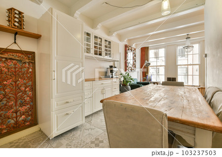 a kitchen and dining area in a house with white cabinets, marble flooring and an ornate wallpaper on the walls a kitchen and dining area in a house with white cabinets, marble flooring and an ornate wallpaper on the walls 103237503