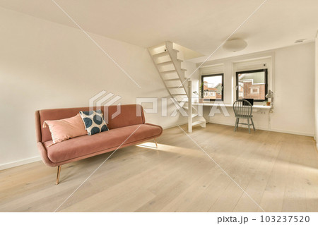 a living room with a pink couch and stairs leading up to the top floor in front of the staircases 103237520