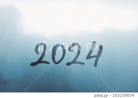 numbers 2024 of new year paint with finger on splashed by rain foggy glass on blue window numbers 2024 of new year paint with finger on splashed by rain foggy glass on blue window 103239074