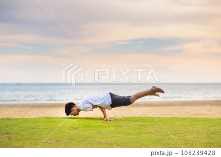 Teenager doing calisthenics exercise. Beach yoga. 103239428