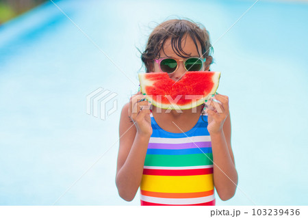 Child with watermelon in swimming pool Child with watermelon in swimming pool 103239436