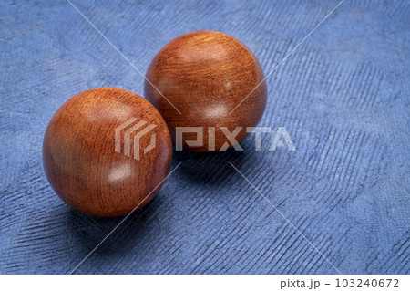 a pair of wooden Chinese medicine balls on textured paper 103240672