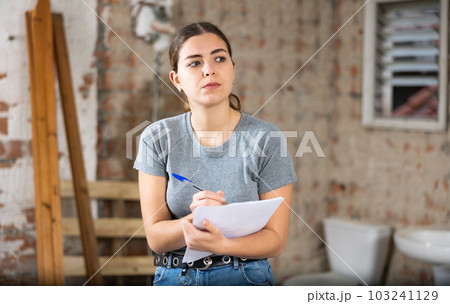 Female architect checking documents in construction site 103241129
