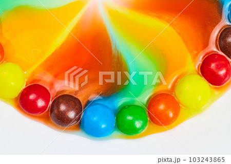 Tie dye colors flowing upward from candy skittles 103243865
