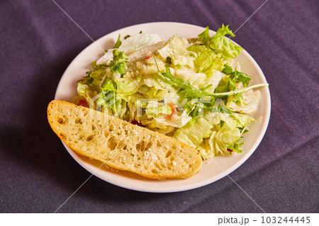 Small side lunch salad with ciabatta white bread slice plain iceberg lettuce parmesan cheese tomato 103244445