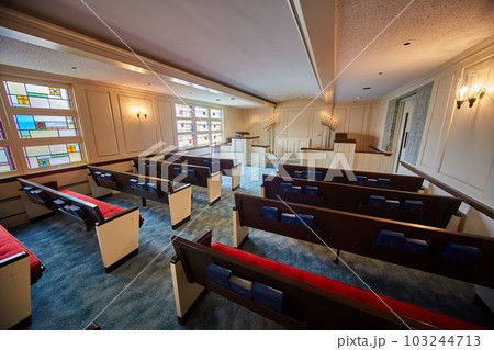 Blue carpeted church with wooden pews, red cushions, bibles, psalms, religious book texts chapel 103244713