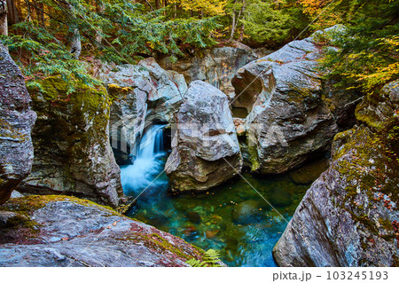 Magical waterfall into blue waters carving through huge rocks in mossy forest Magical waterfall into blue waters carving through huge rocks in mossy forest 103245193