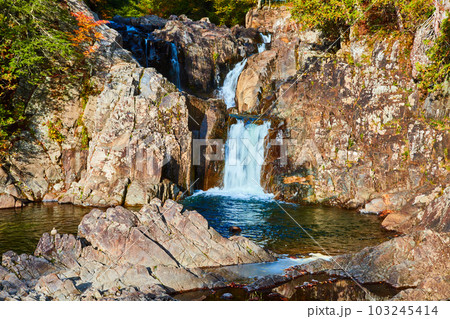Looking up at waterfalls pouring through rocks in forest 103245414