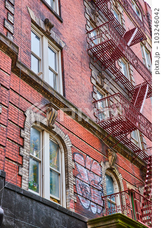 Looking up old brick building in New York City with metal steps up side 103246042