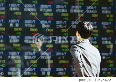 屋外の株価ボードの電光掲示板を見る30代のビジネスマン投資家男性の後ろ姿 103246721
