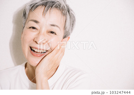 頬を触る笑顔のグレイヘア女性・スキンケアイメージ 103247444