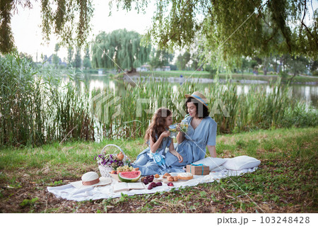 A mother and daughter on a picnic in a park on the banks of a river 103248428