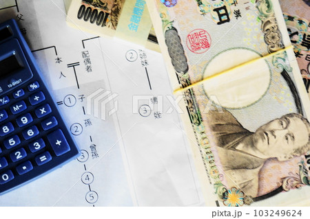 等親図の上に置かれた一万円札と電卓、相続イメージ 103249624