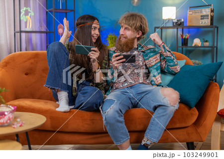 Happy family married couple man woman playing shooter video app games online on smartphone at home Happy family married couple man woman playing shooter video app games online on smartphone at home 103249901