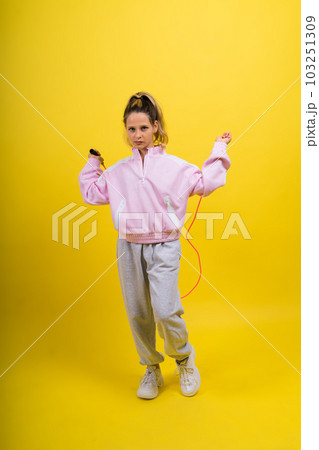 Adorable female child with skipping rope jumping in studio Adorable female child with skipping rope jumping in studio 103251309