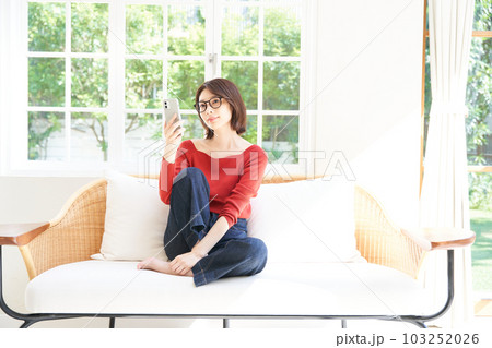 私服の若い女性 リビング スマホ 私服の若い女性 リビング スマホ 103252026