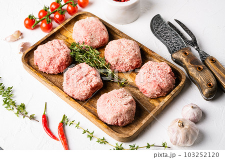 Raw chicken cutlets, ground meat patty, on white stone table background Raw chicken cutlets, ground meat patty, on white stone table background 103252120