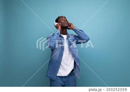 cool dude american man with dreadlocks in a denim jacket relaxes to music in headphones cool dude american man with dreadlocks in a denim jacket relaxes to music in headphones 103252359