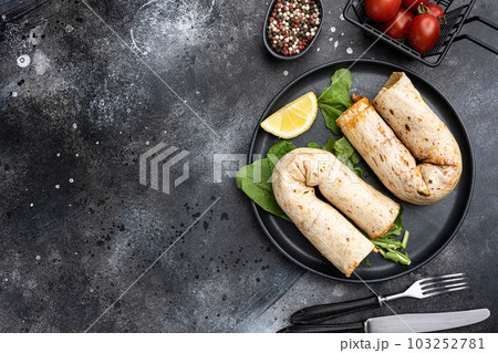 Street food chicken tantuni Turkish doner, on black dark stone table background, top view flat lay, with copy space for text 103252781