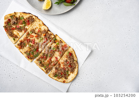 Turkish pide with minced lamb, tomatoes, bell pepper, on gray concrete table background, top view flat lay, with copy space for text 103254200