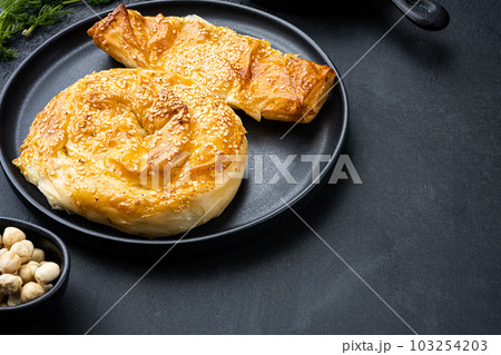 Burekas filled with cheese painir , on black dark stone table background, with copy space for text 103254203