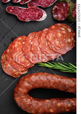 Set of dry cured salami, spanish sausages, slices and cuts on black background, flat lay Set of dry cured salami, spanish sausages, slices and cuts on black background, flat lay 103254755